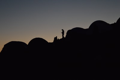 一个人的剪影晚上斜坡上的露营地
